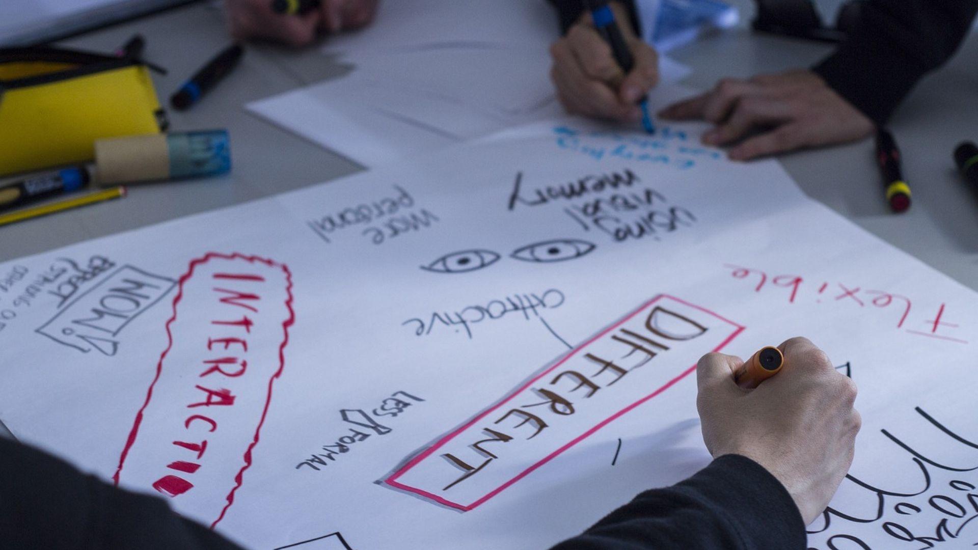 People writing on paper all the ways that being different benefits the workplace.