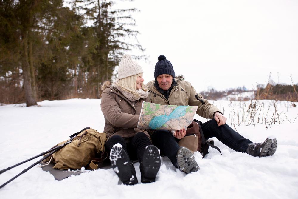 Two People are pictured resting on the snow while they look at their map