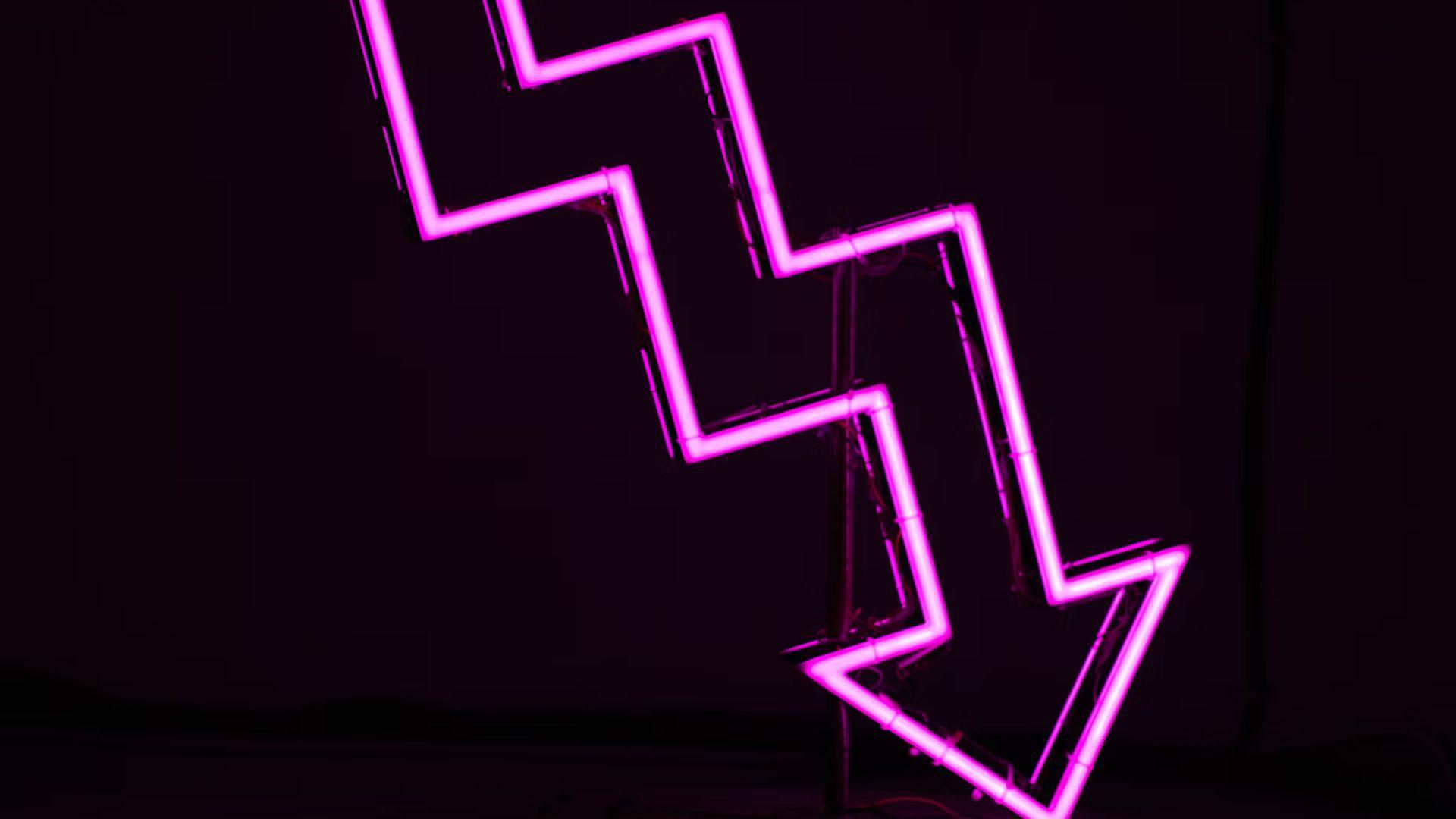 A pink neon arrow gradually pointing down against a black background.