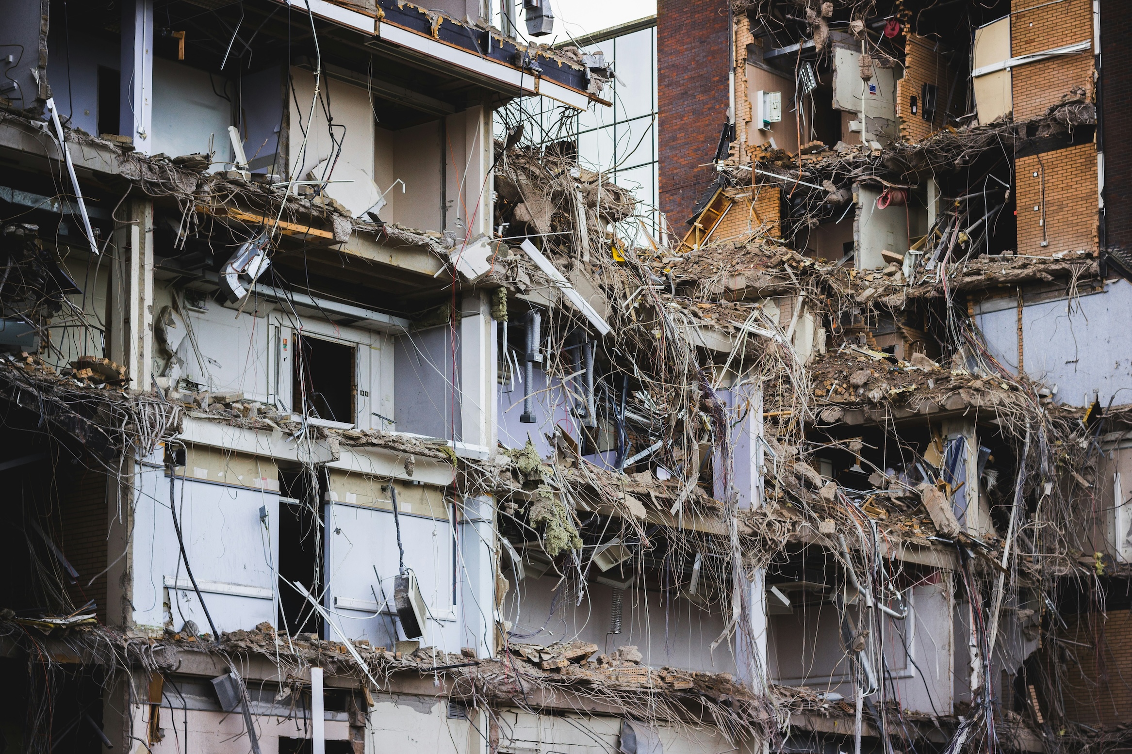 The facade of an office block removed to expose office spaces, cables, rooms and the structure.