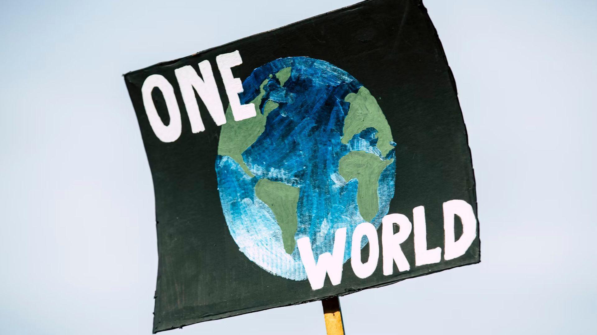 A sign with an image of the Earth in the center and “One world” in white writing.
