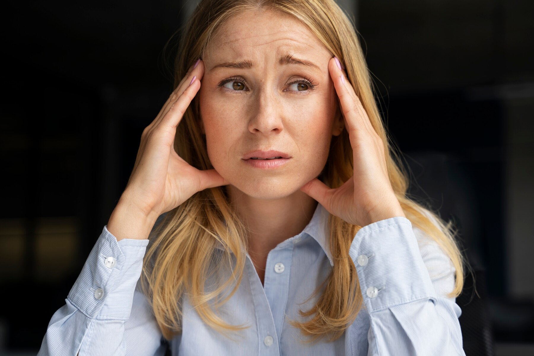 woman with both hands on either side of her face with a worried expression