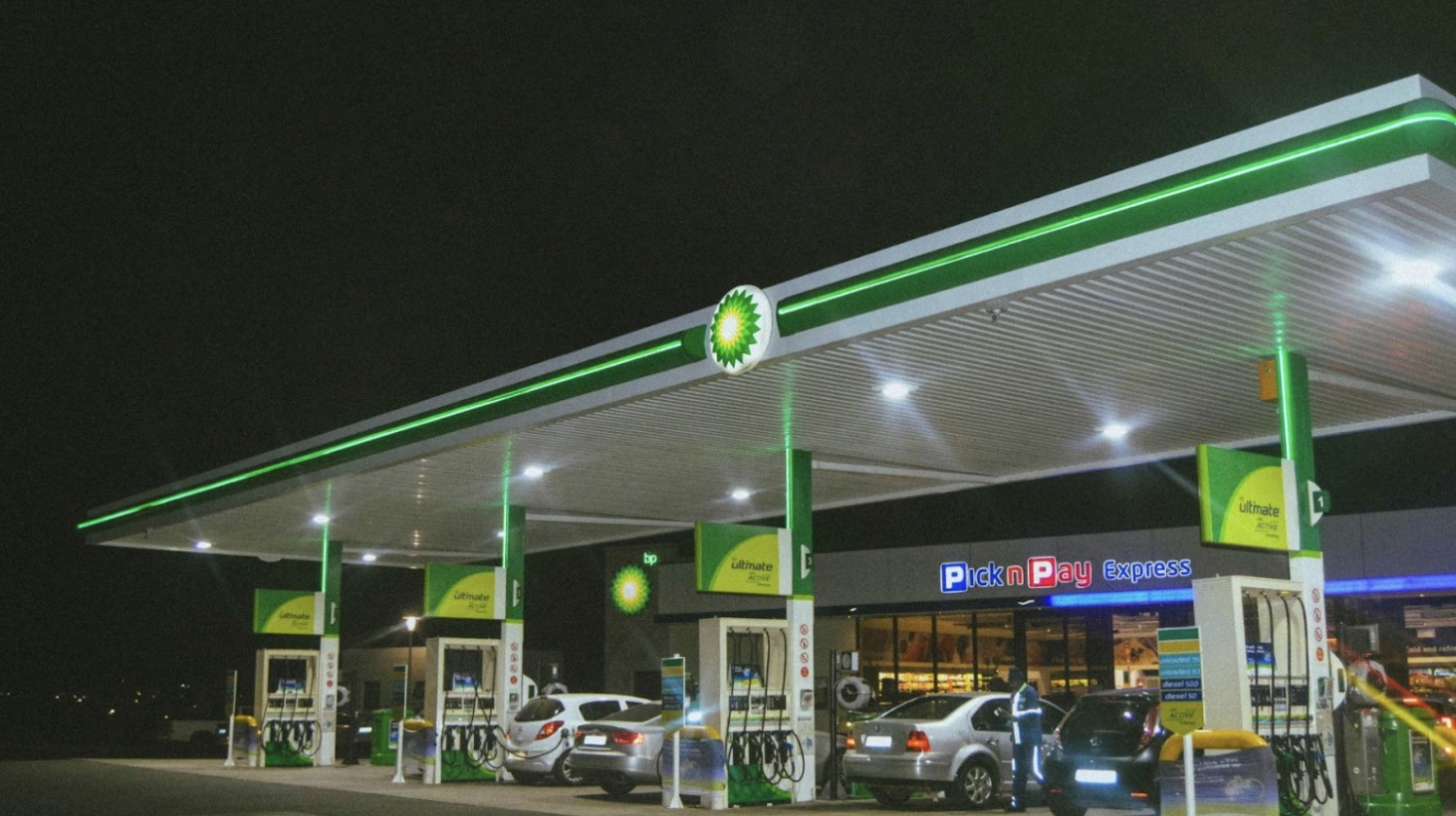 Many cars at a gas station at night.