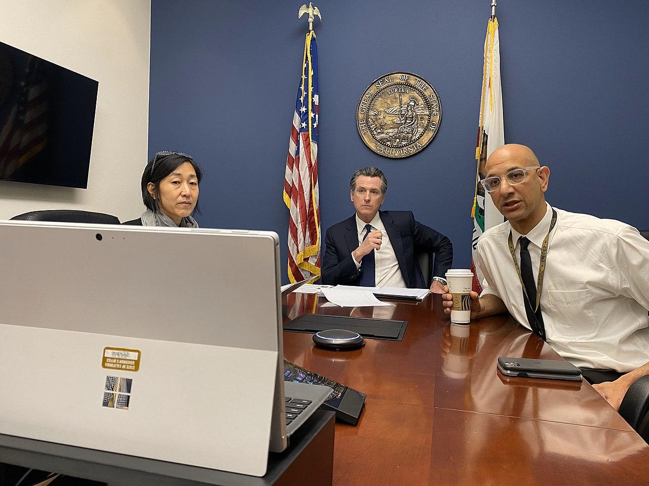 Gavin Newsom pictured at the end of a table alongside his advisors
