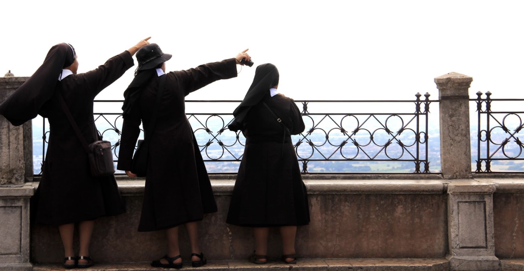 Three nuns standing and looking at a view in Italy.