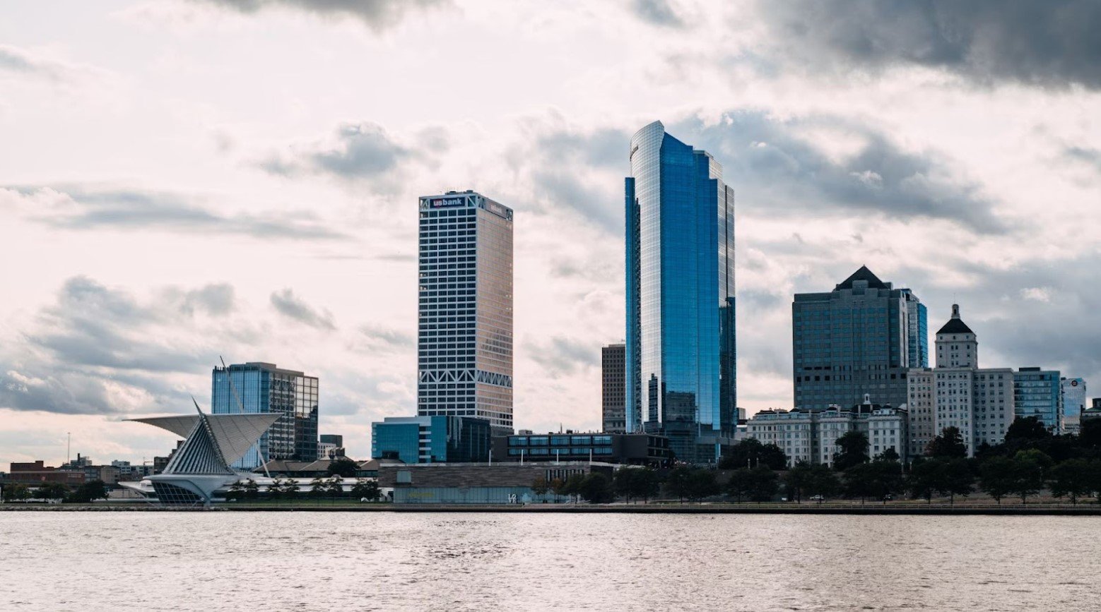 A view of downtown Milwaukee, Wisconsin, over a body of water. The city contains lots of high-rise buildings.