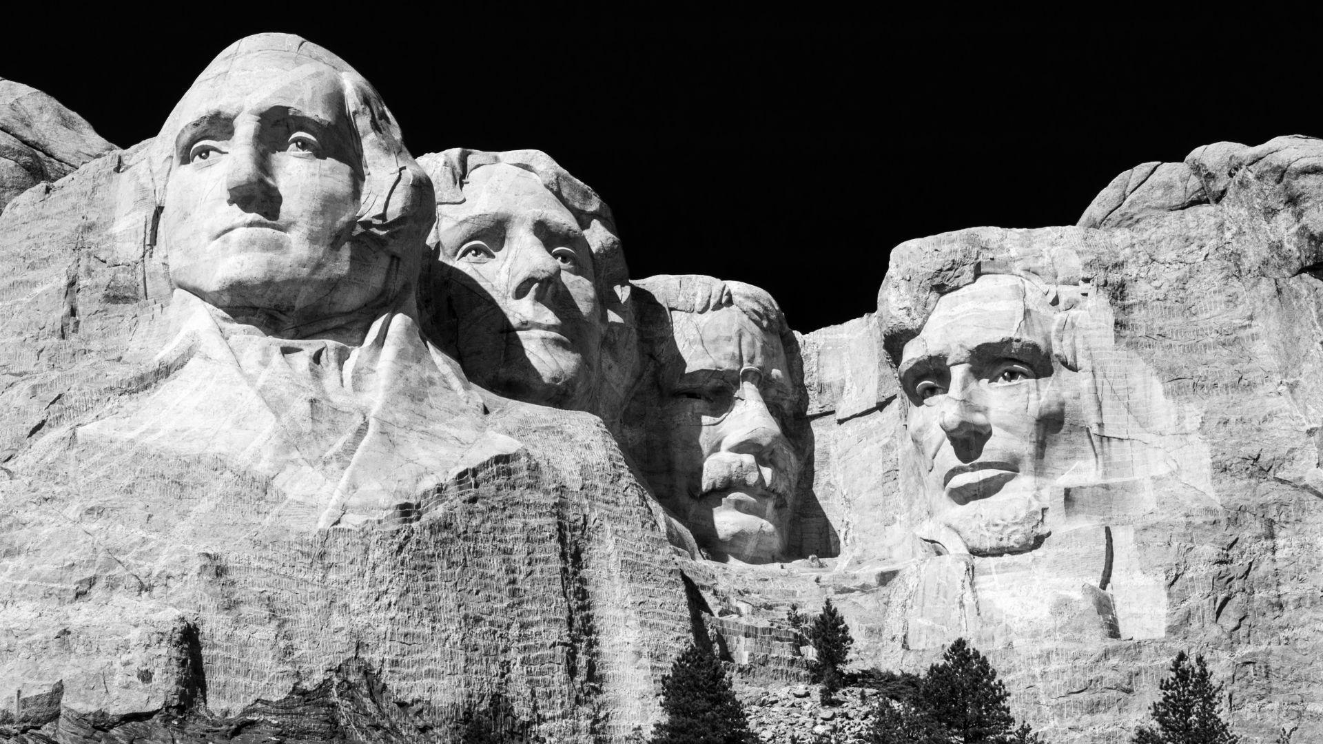 A black and white photo of Mount Rushmore with carvings of presidents’ heads.
