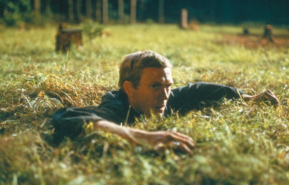 Captain Virgil Hilts (Steve McQueen) looking out from a tunnel in the grass