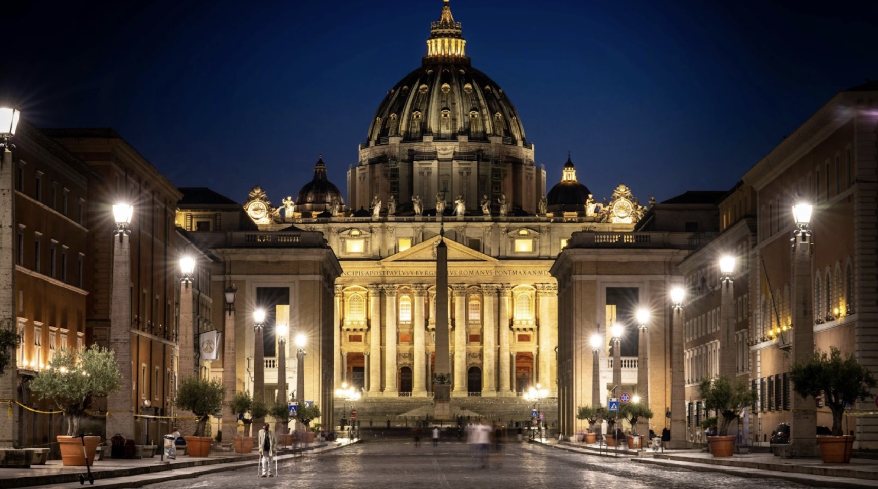 People walking around the streets of Vatican City in the evening.