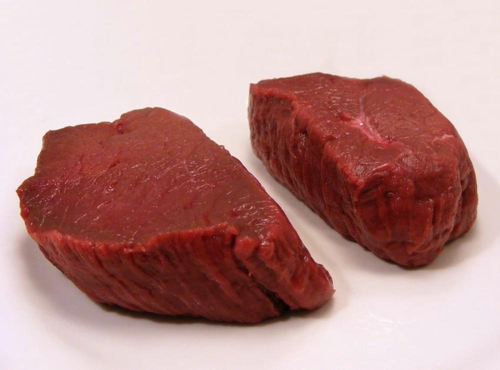 A photograph of two large venison steaks on a table
