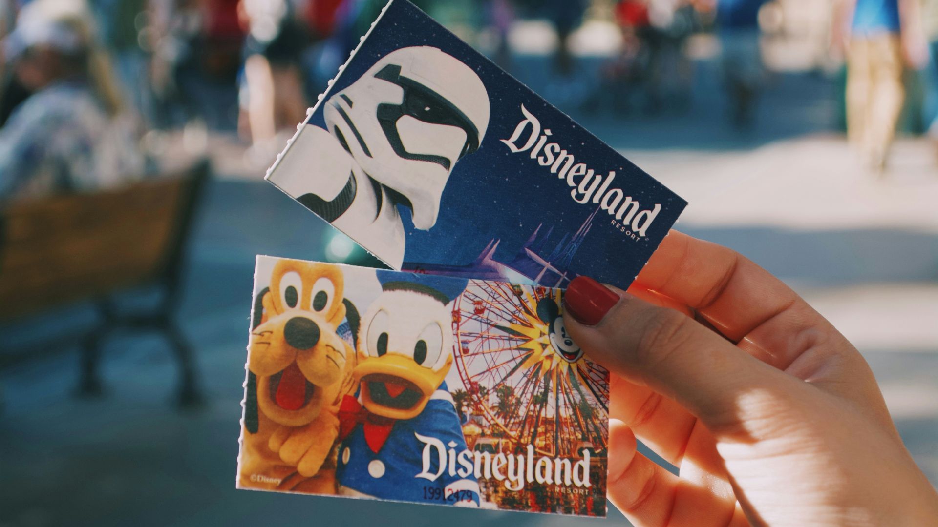A close-up of a person holding two Disneyland passes.