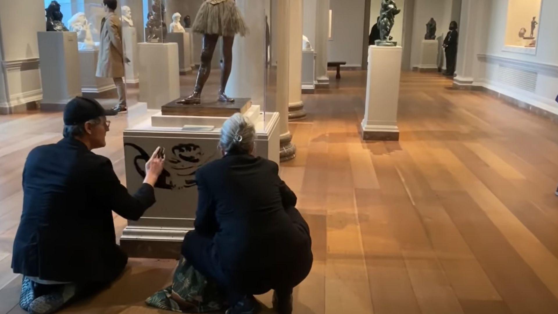 Joanna Smith and Timothy Martin destroying Little Dancer Aged Fourteen. They are smearing black paint on the base of the statue.
