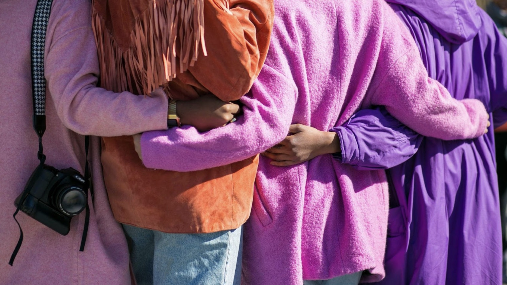 A group of women standing with their arms around each other.