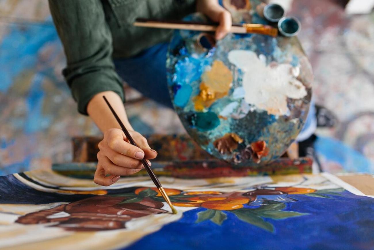 A faceless artist painting a still life on canvas