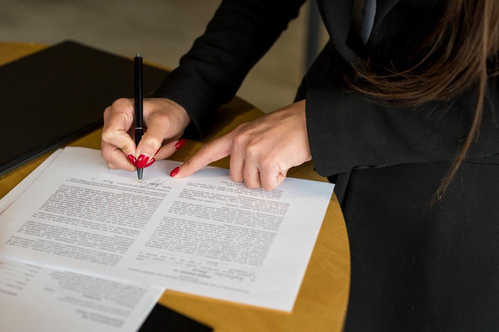 A woman is pictured signing a sheet of paper