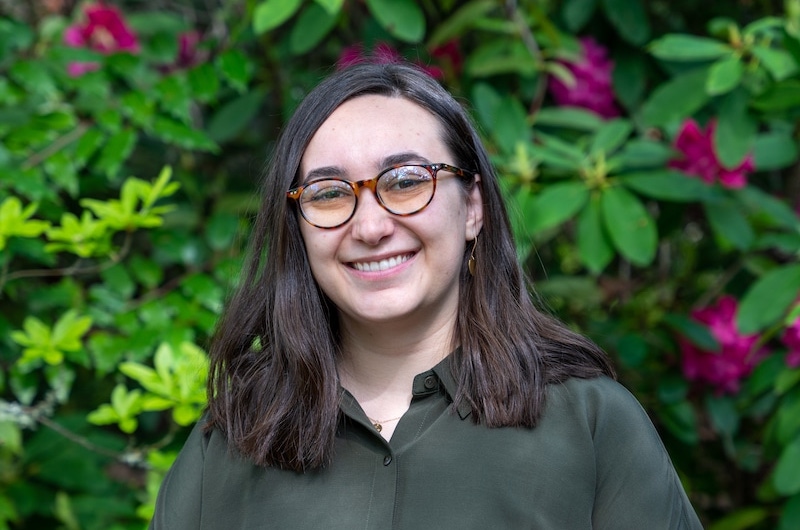 A headshot of Katie Stelling standing infront of a shrub