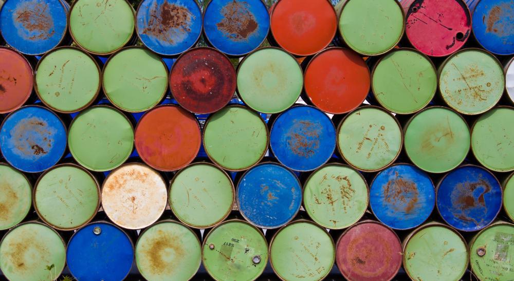A photograph of numerous gasoline barrels stacked atop each other