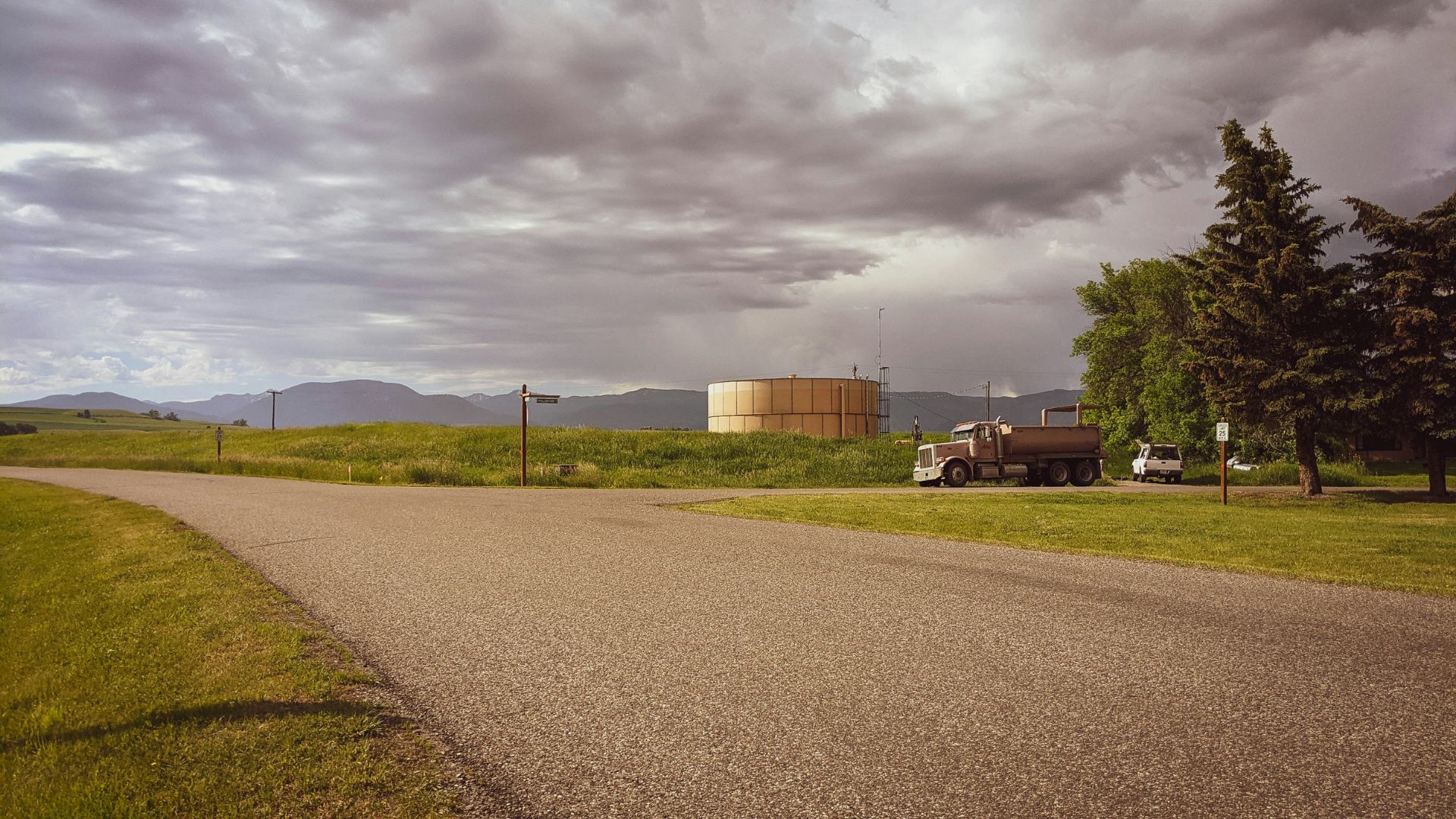 Cars parked on the side of a road near green grass in Bozeman, Montana.