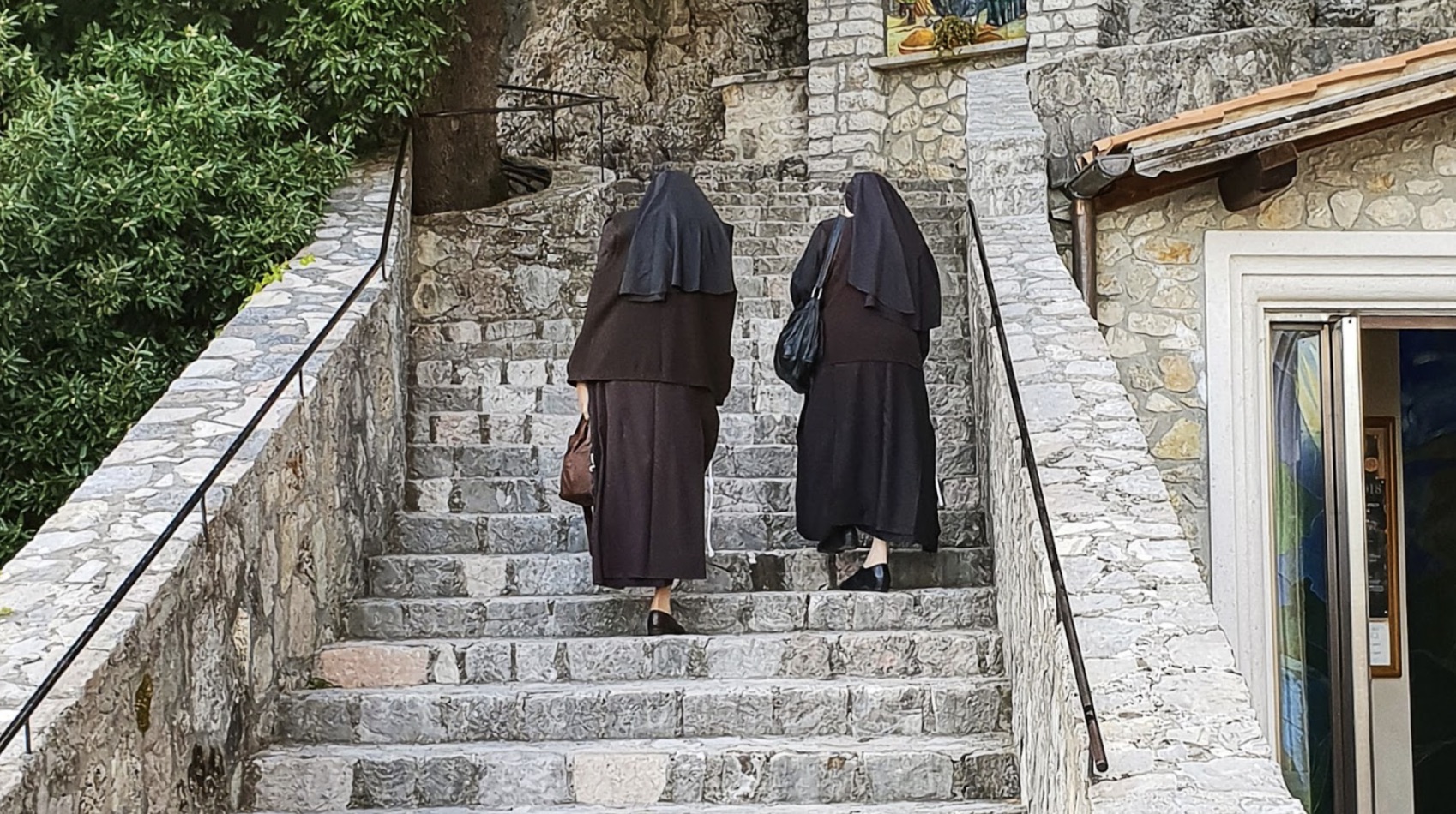 Two nuns in Italy walking up the stairs.