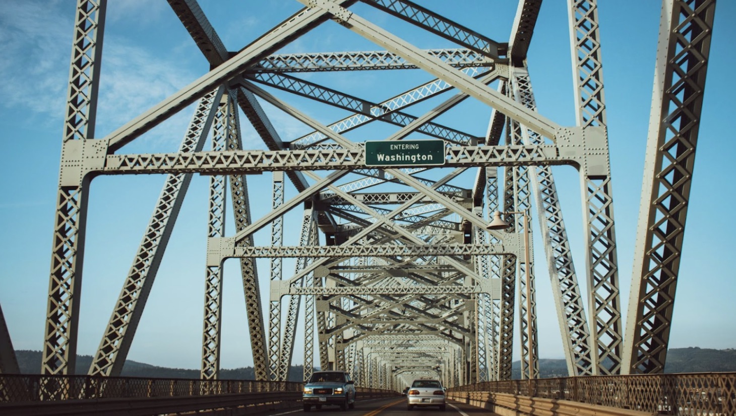 Cars on a bridge entering Washington state in the daytime.
