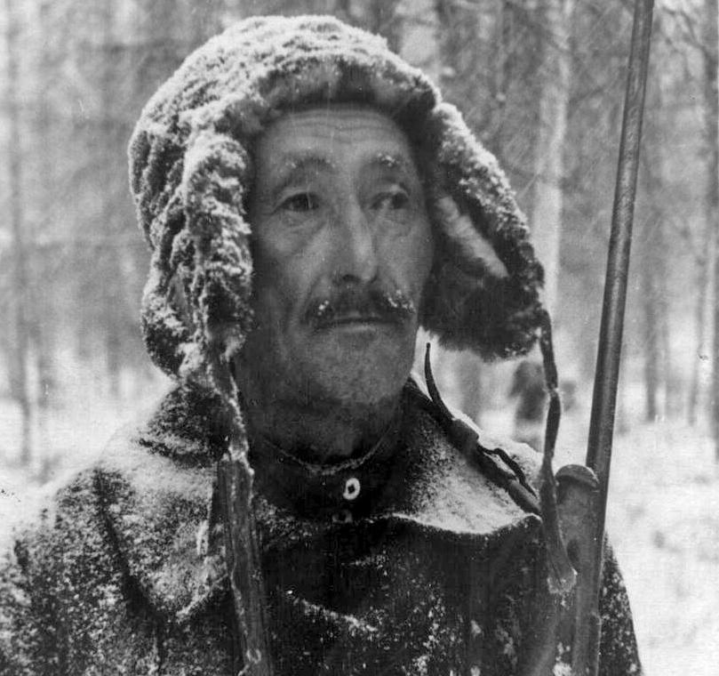 A photograph of a Yakut hunter dressed in warm clothing and with a rifle