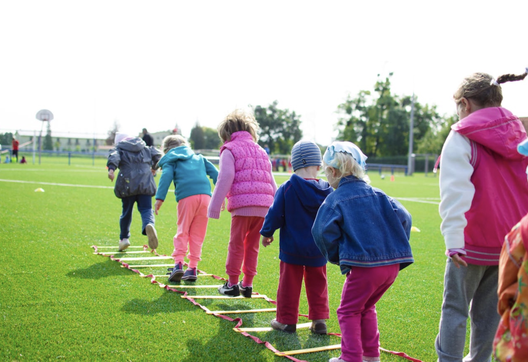 An image of several children playing outside on a grassy area