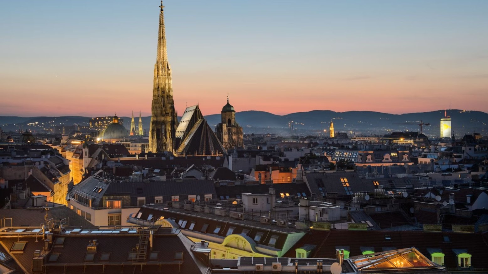 A view of Vienna in the evening. A cathedral is in the distance, with its tower above the rest of the city.