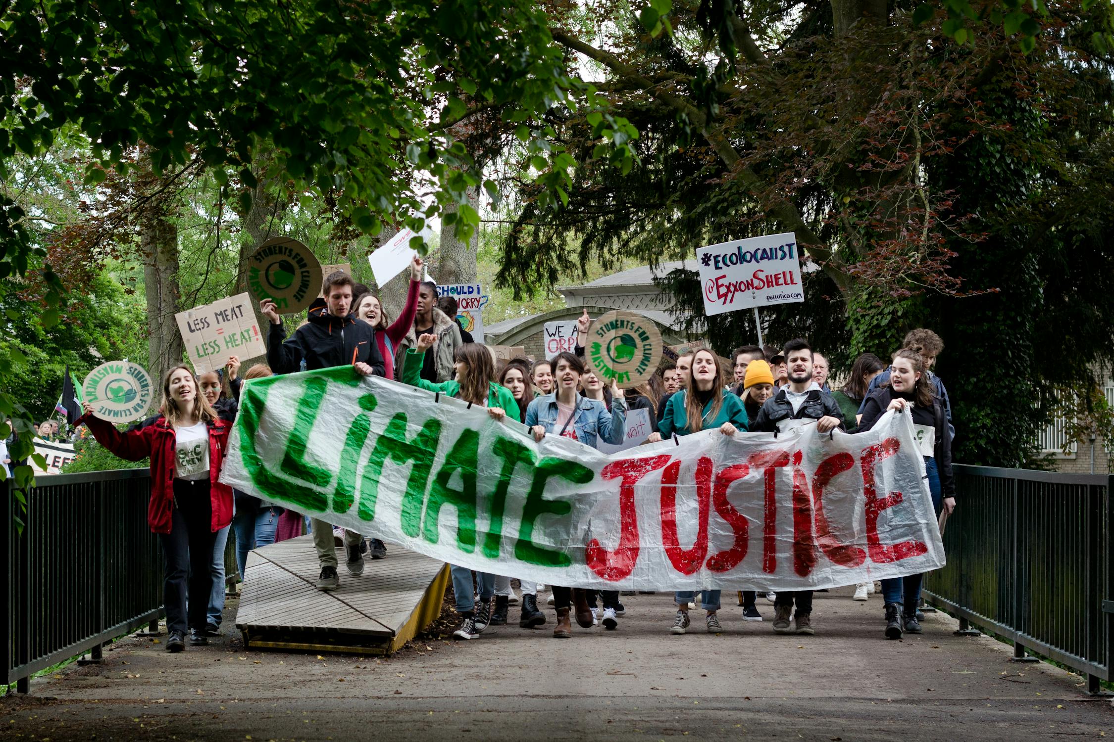 A group of climate protestors walking down a street with signs