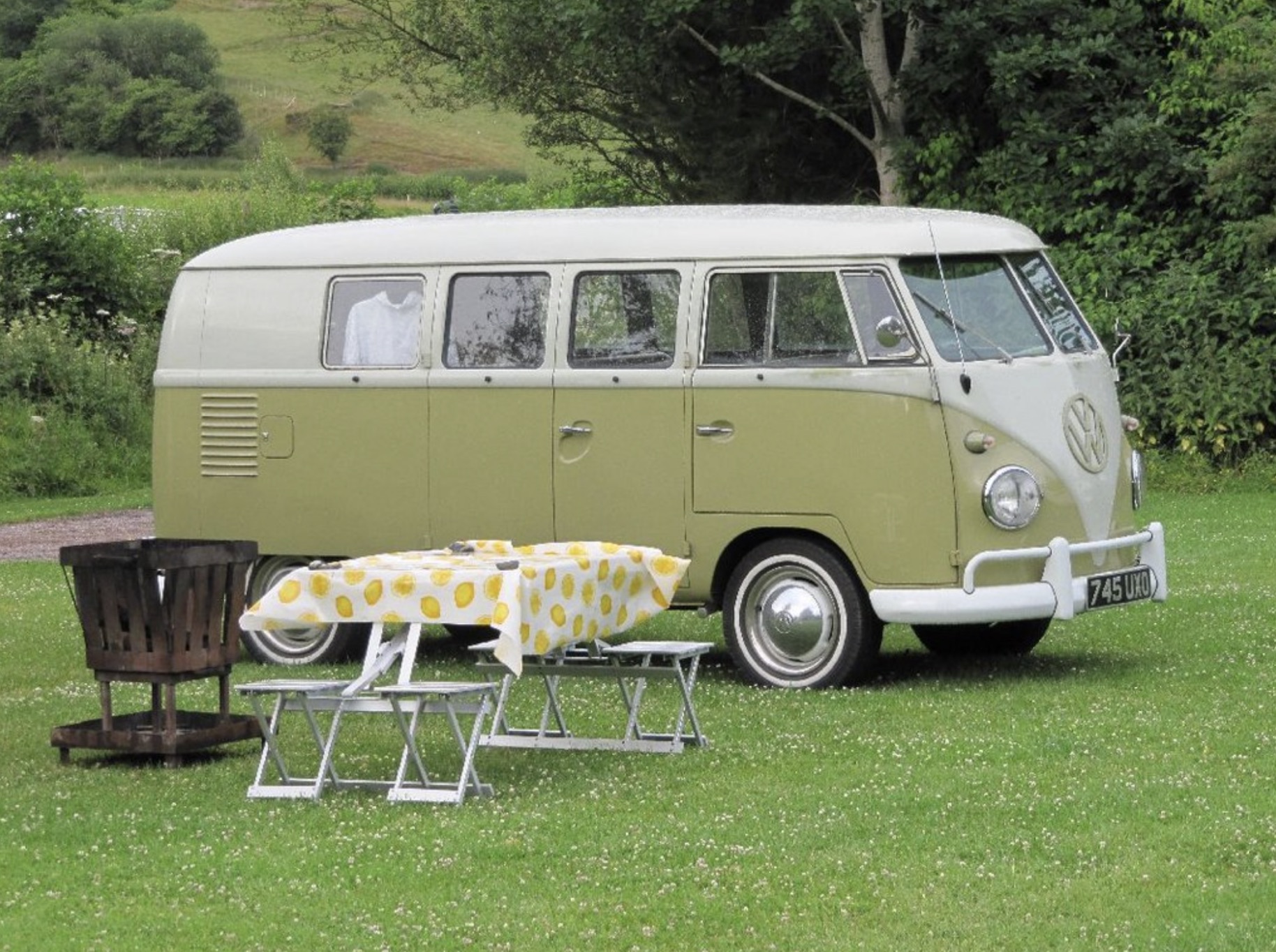 An image of a small green Volkswagen camper parked on the grass