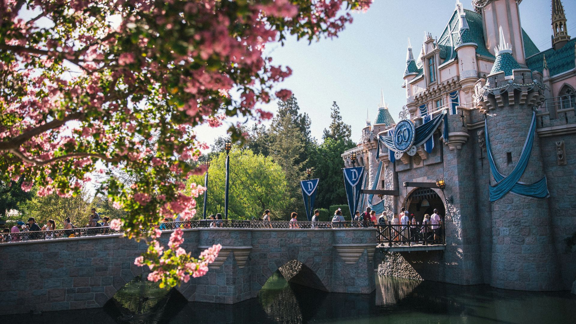 Many people walking through the entrance of Disneyland.