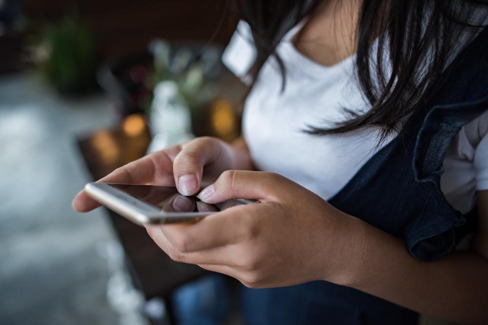 A photograph of a woman using her smartphone