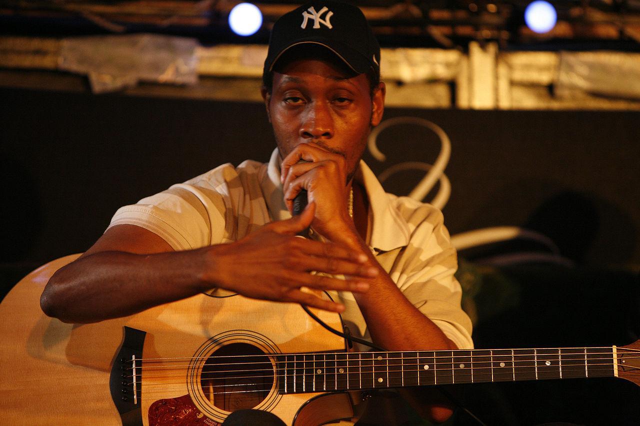 A photograph of producer RZA on stage with a guitar