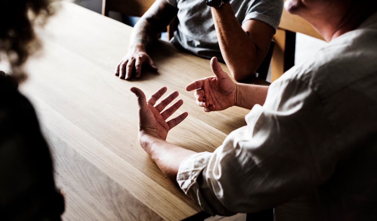 three people sitting at a table having a discussion