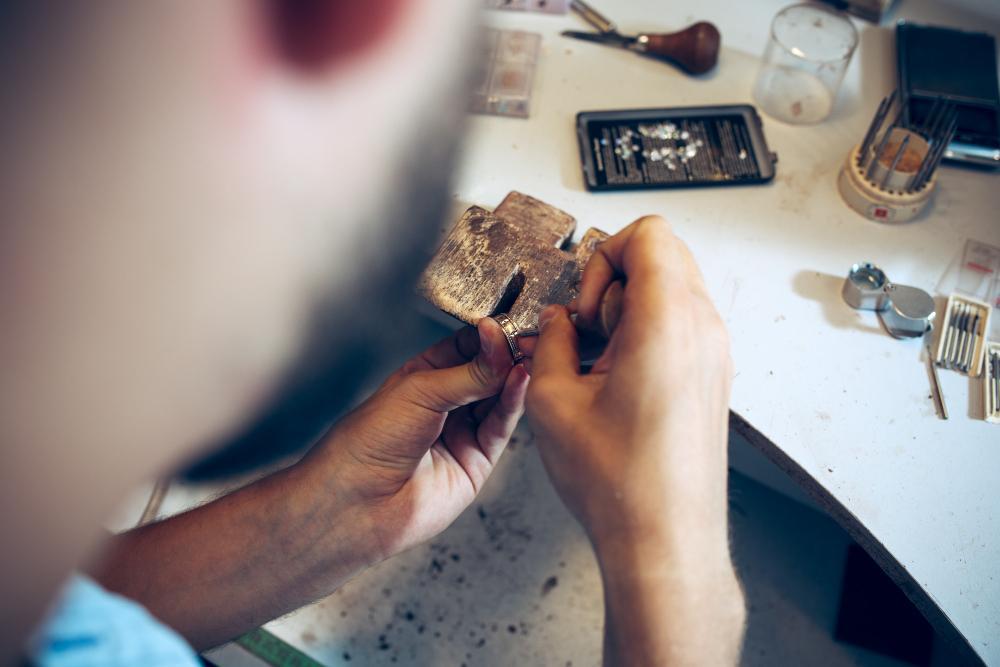 A man is pictured working on a silver item