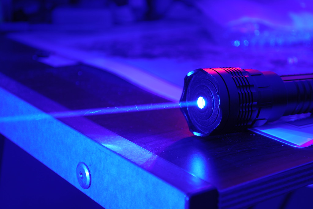 A blue-tinted room with a flashlight pointing a laser beam across the room