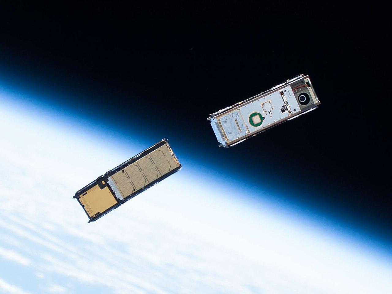 A photograph of two small satellites in space