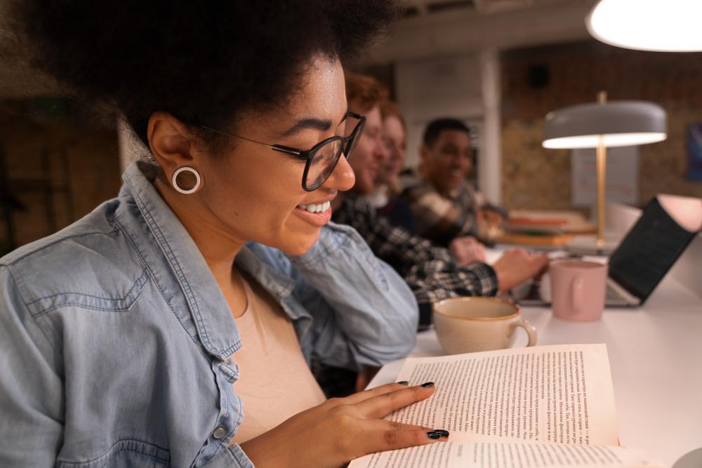 Several students are pictured reading at tables in a library