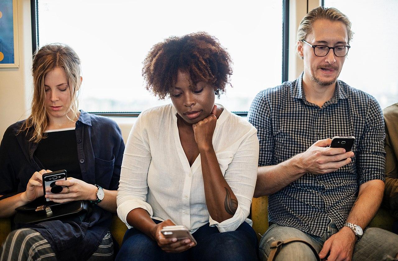 Three people pictured using their smartphones on a train