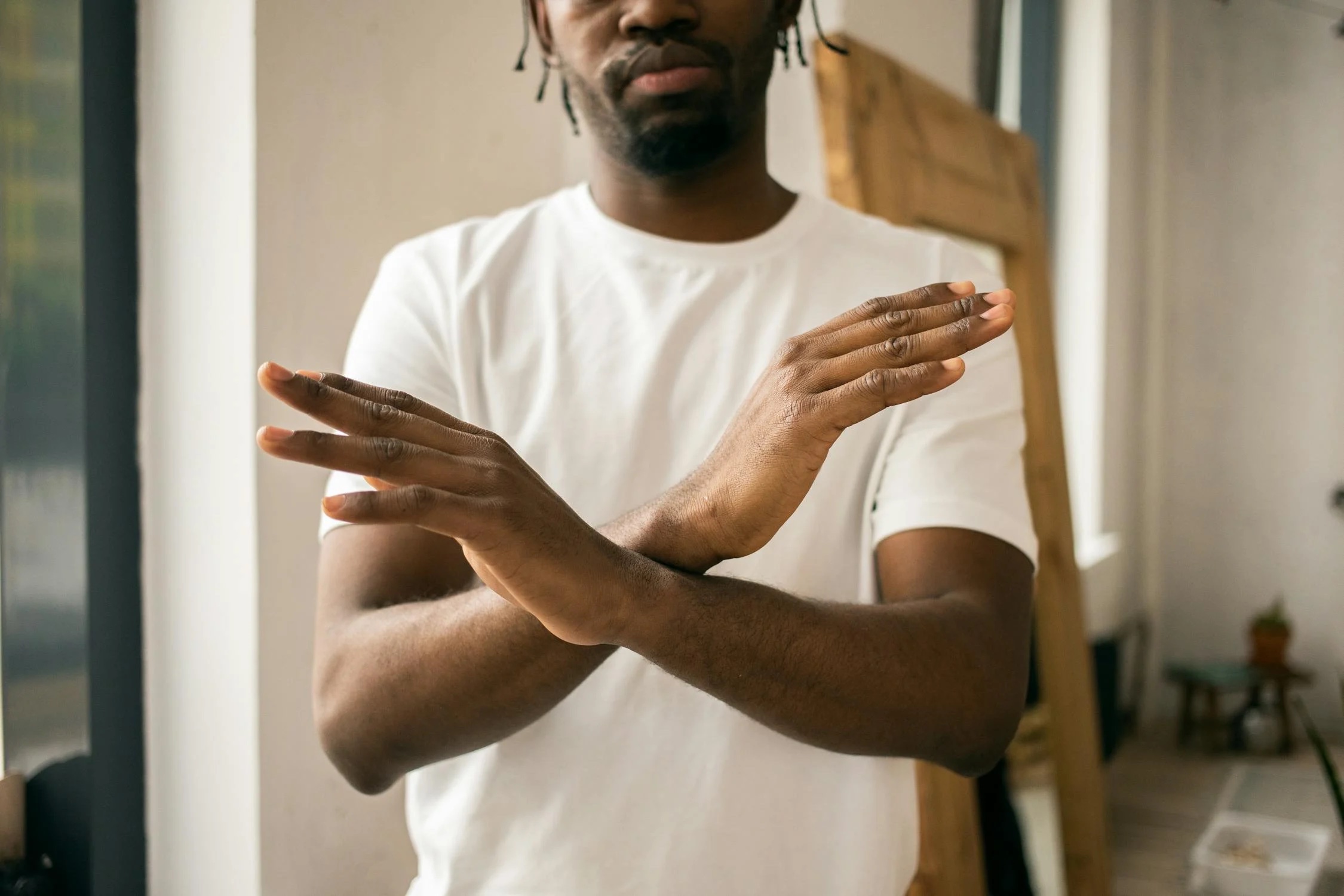 Faceless black man showing stop gesture with crossed hands