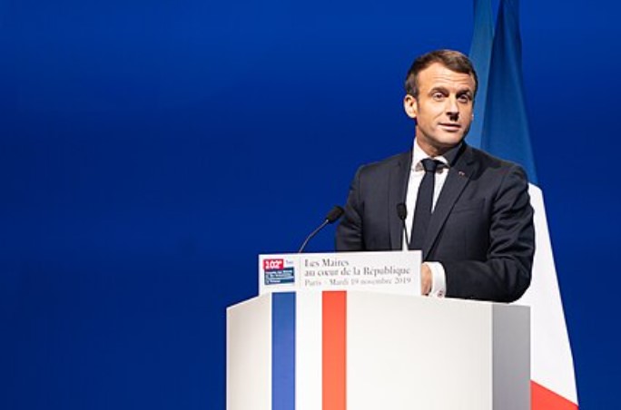 Macron speaking on podium with blue background