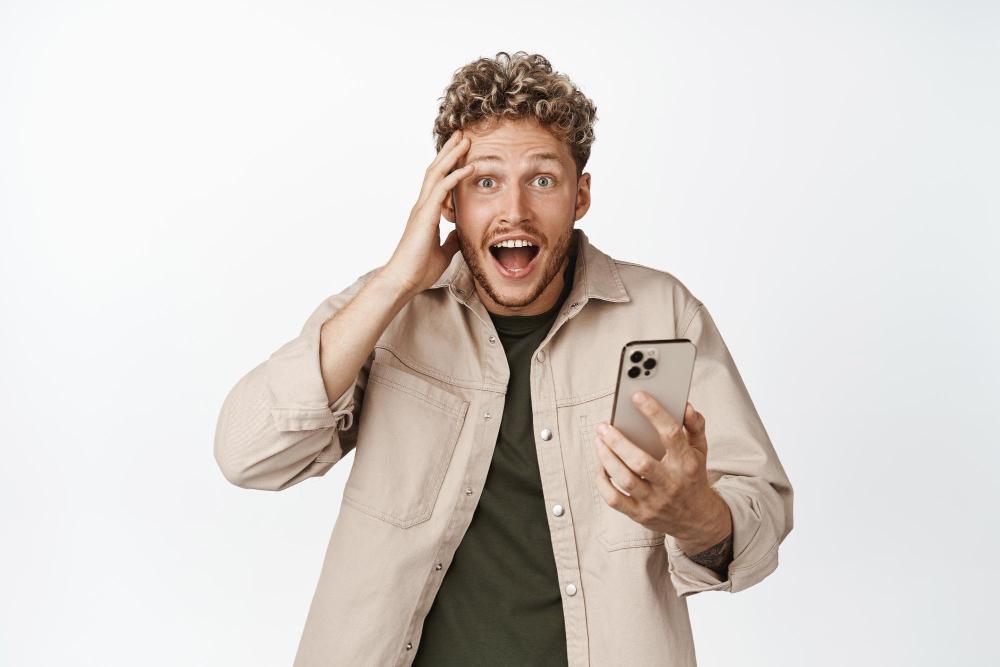 A man appears visibly shocked while using his phone