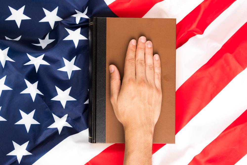 A man's hand is pictured atop a book placed on the American flag