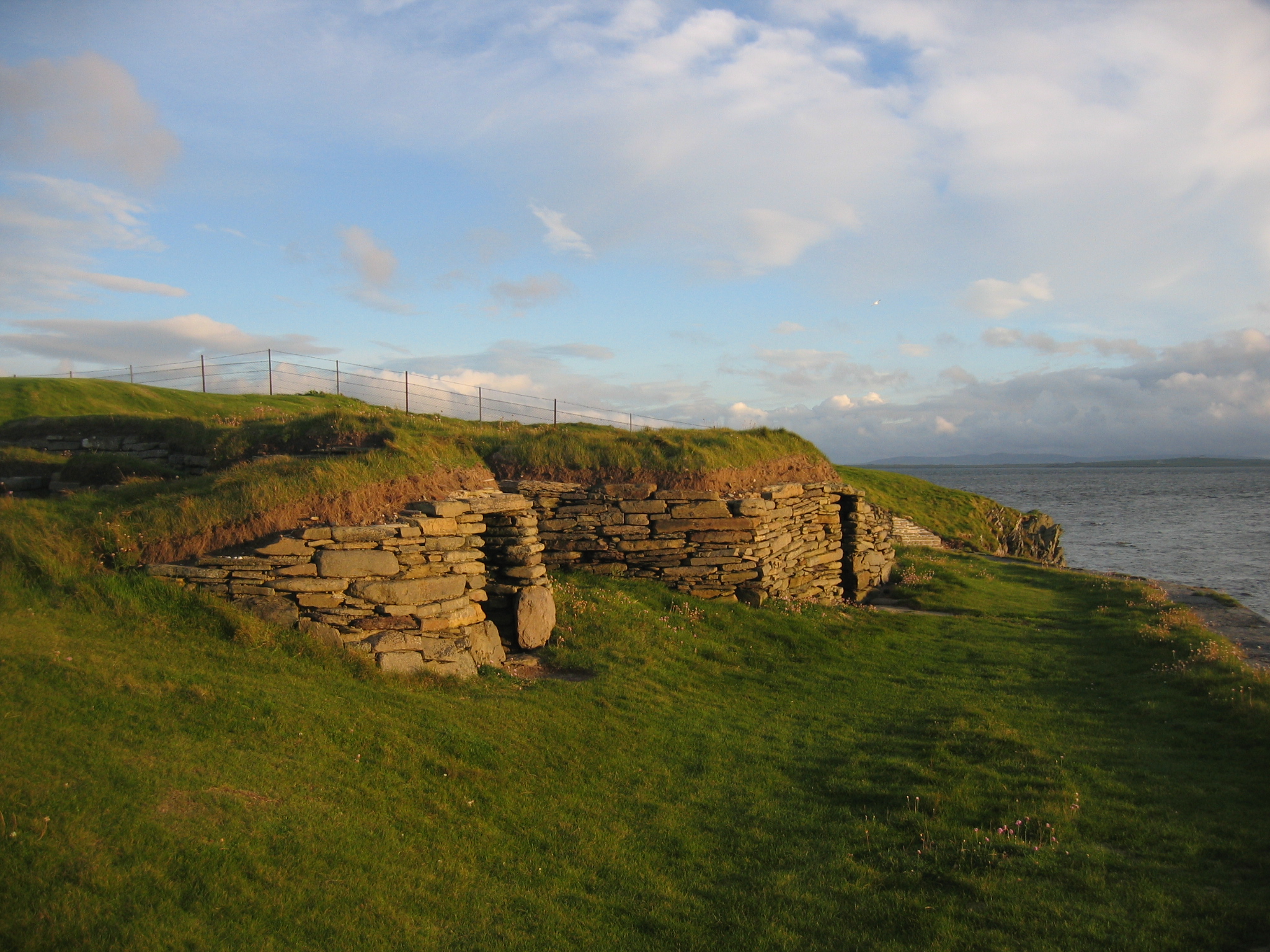 A wide shot of The Knap of Howar near the edge of a hillside