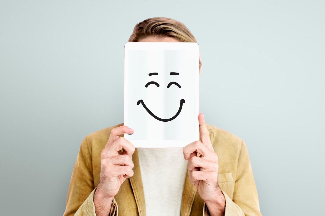man holding a piece of paper in front of his face with a smiling face drawn on it