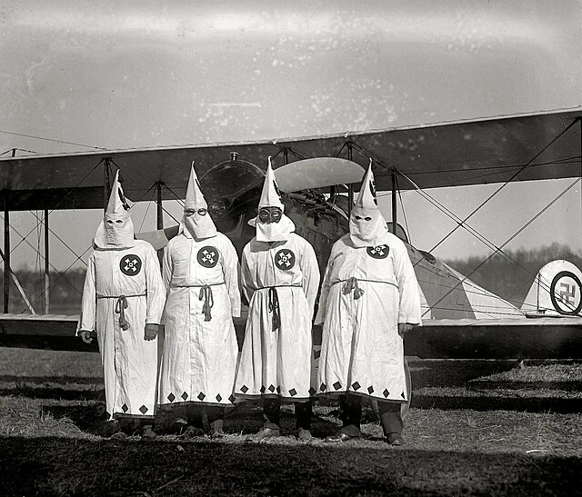 Ku Klux Klan members in front of an aircraft