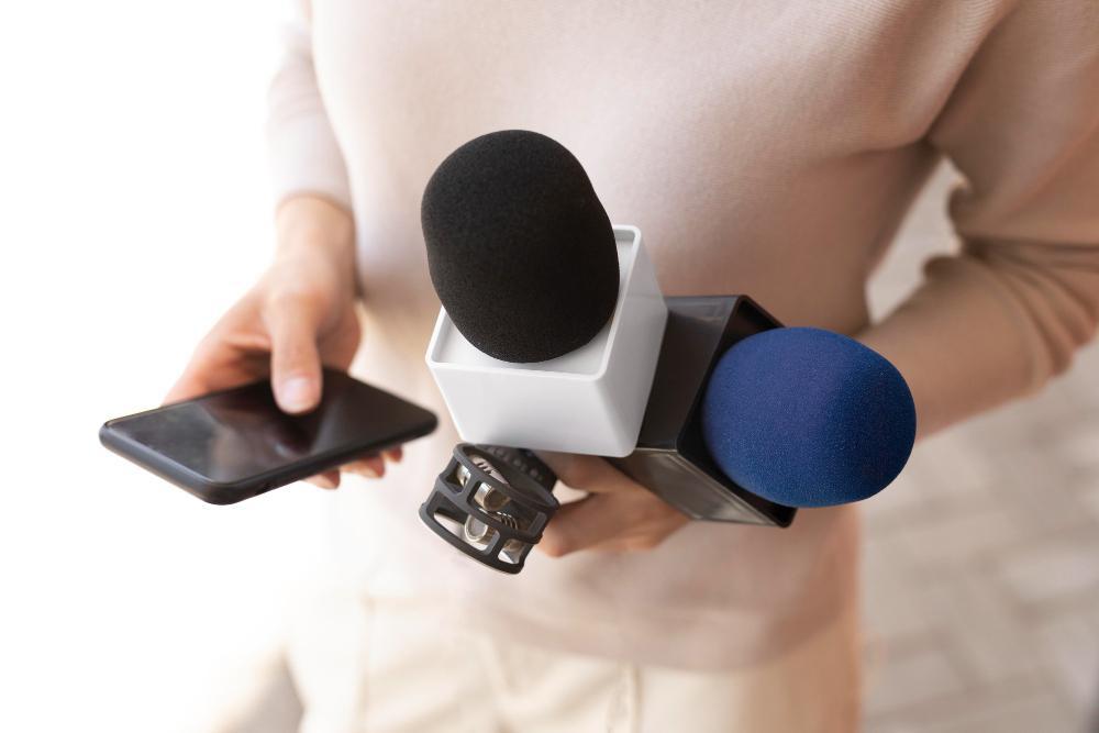 A man is pictured holding two mics as he prepares for an interview