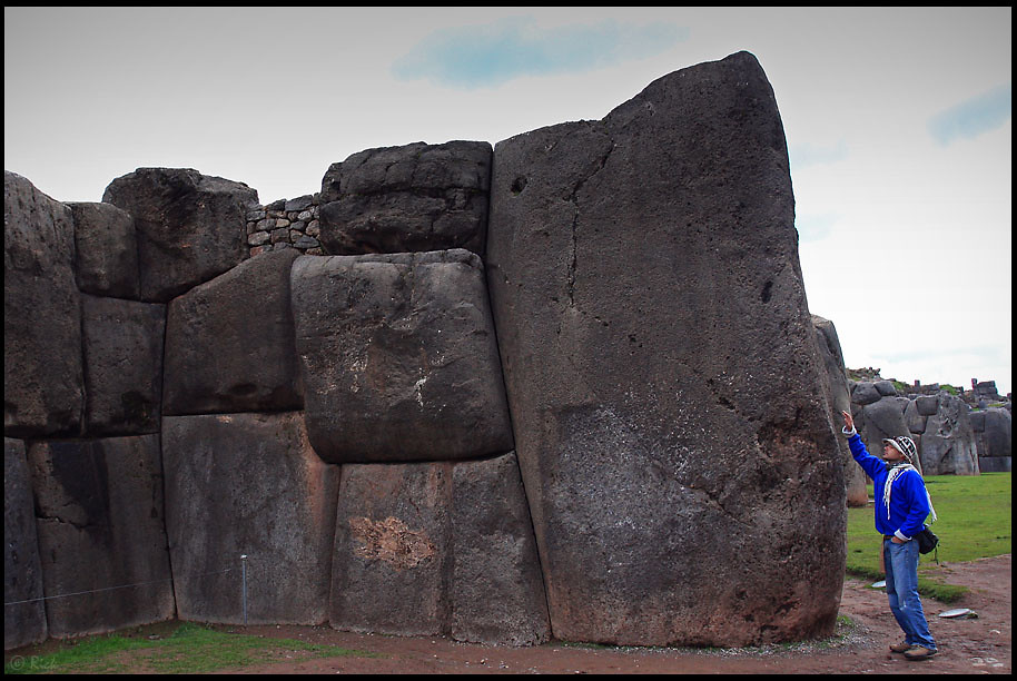 A tourist with a hand on a the stones of Sacsayhuamán