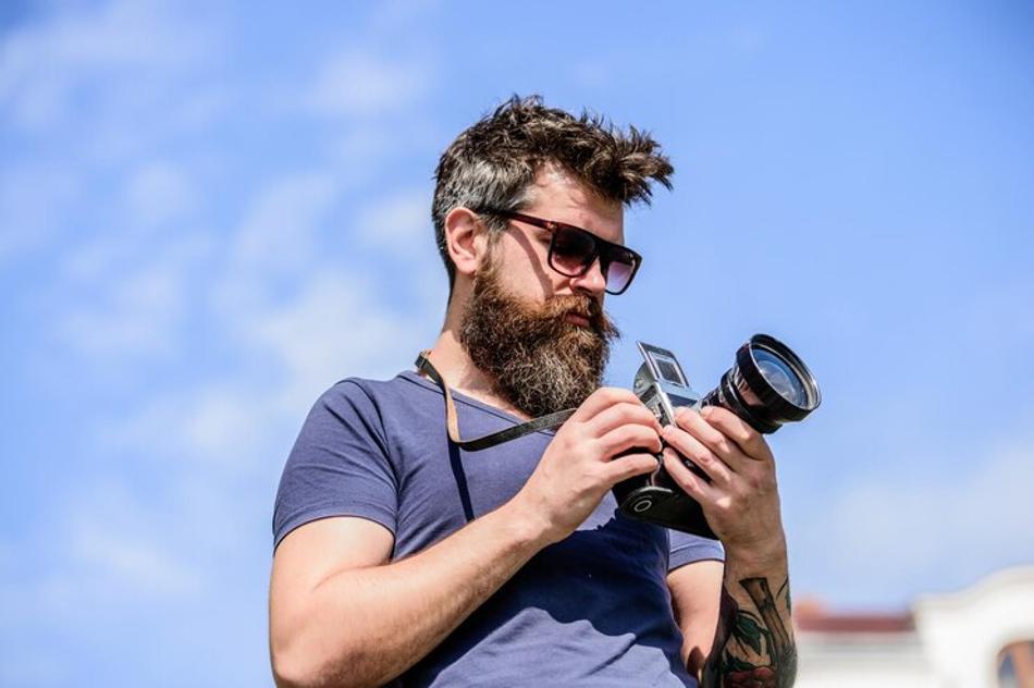 A photograph of a man with a long beard testing his camera