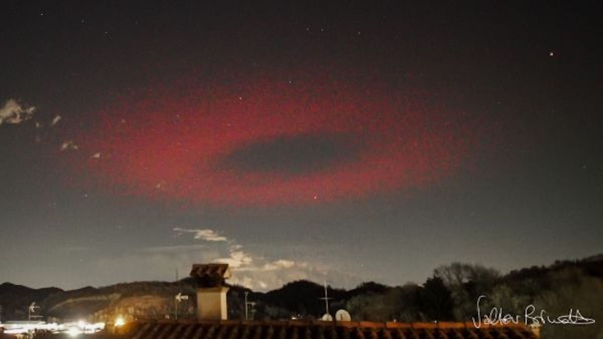 A ring of red light appears to hang above an Italian town.