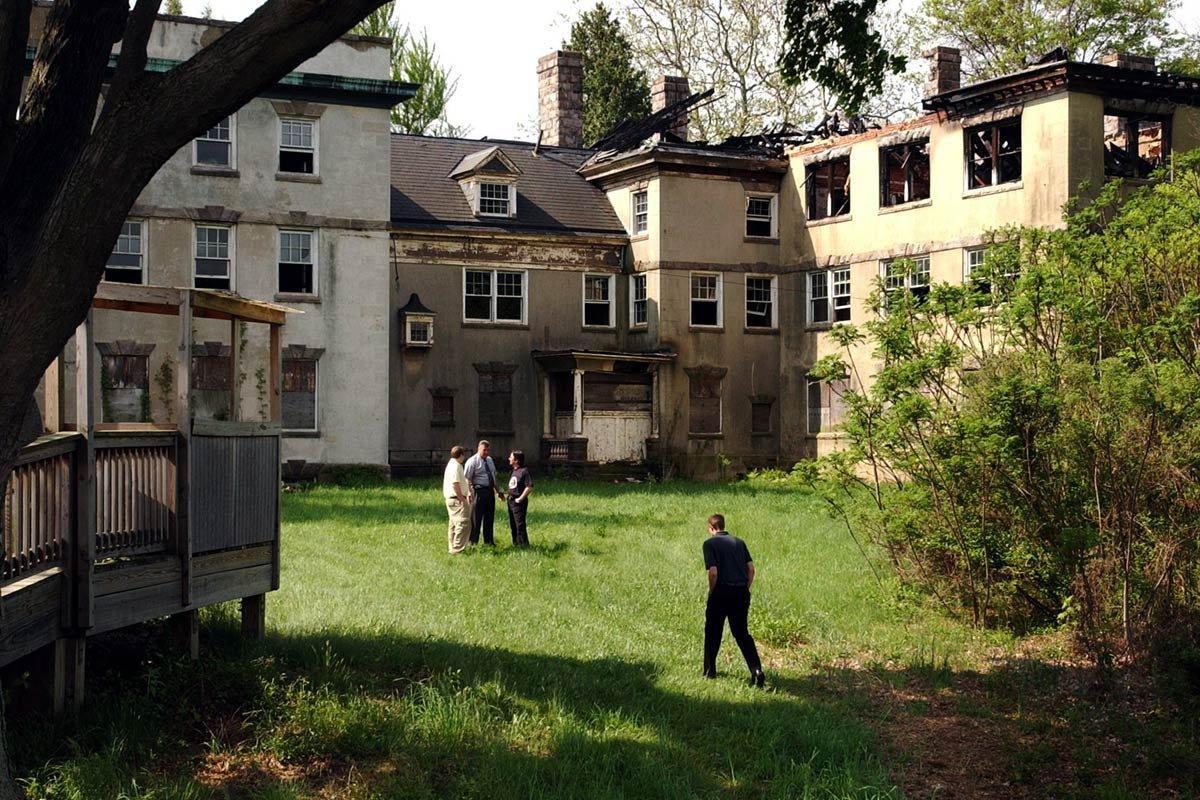 A photograph of 4 men standing just outside of McNeal mansion during a sunny day